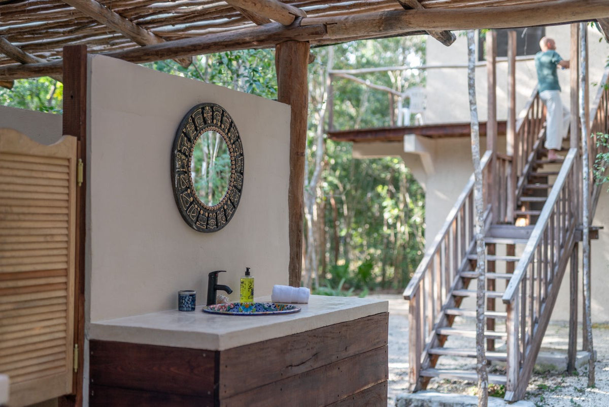 Lavabo y escaleras del refugio abiertos al paisaje de la selva.