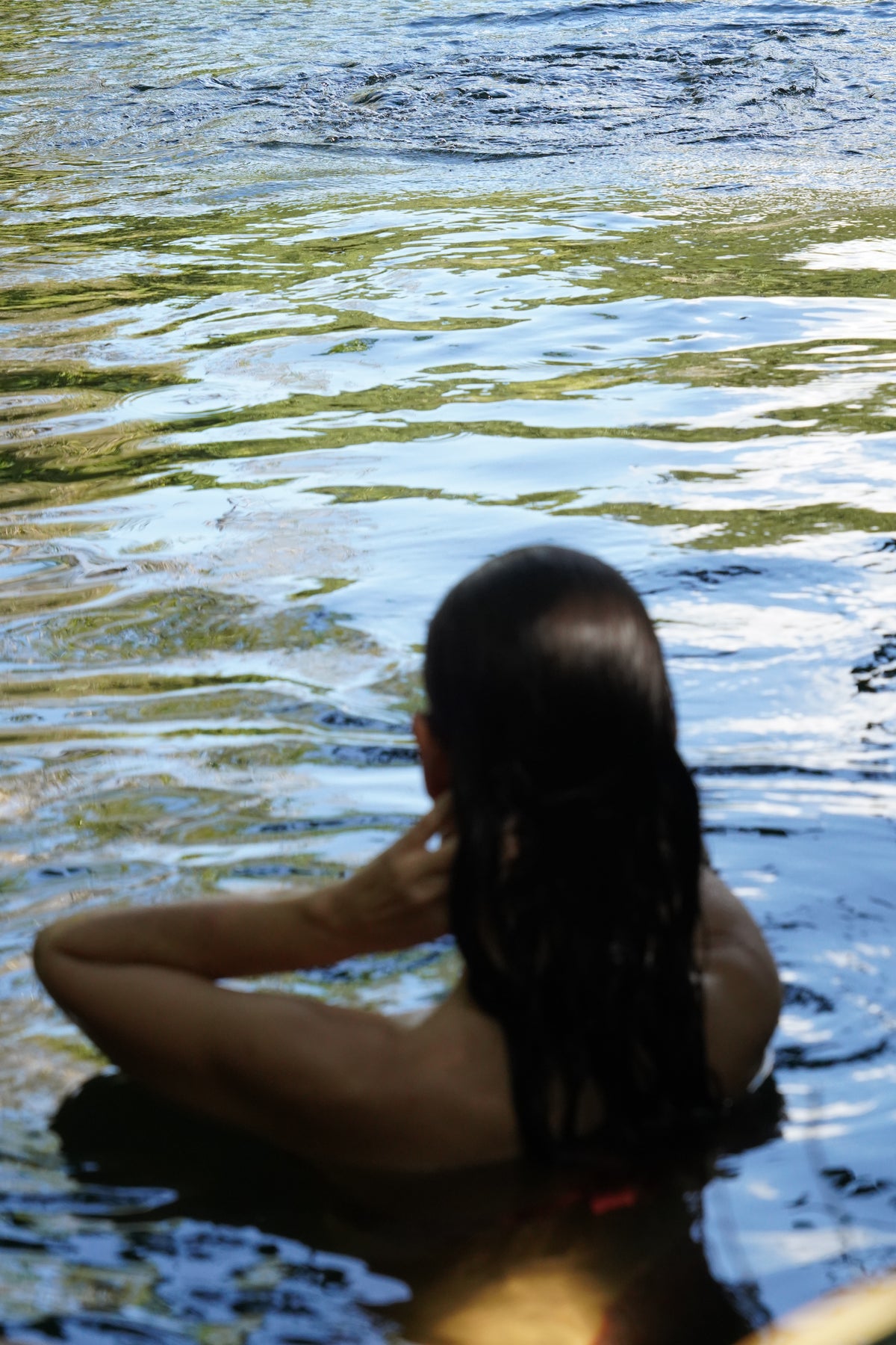 Participante de espaldas sumergida en el agua del cenote.