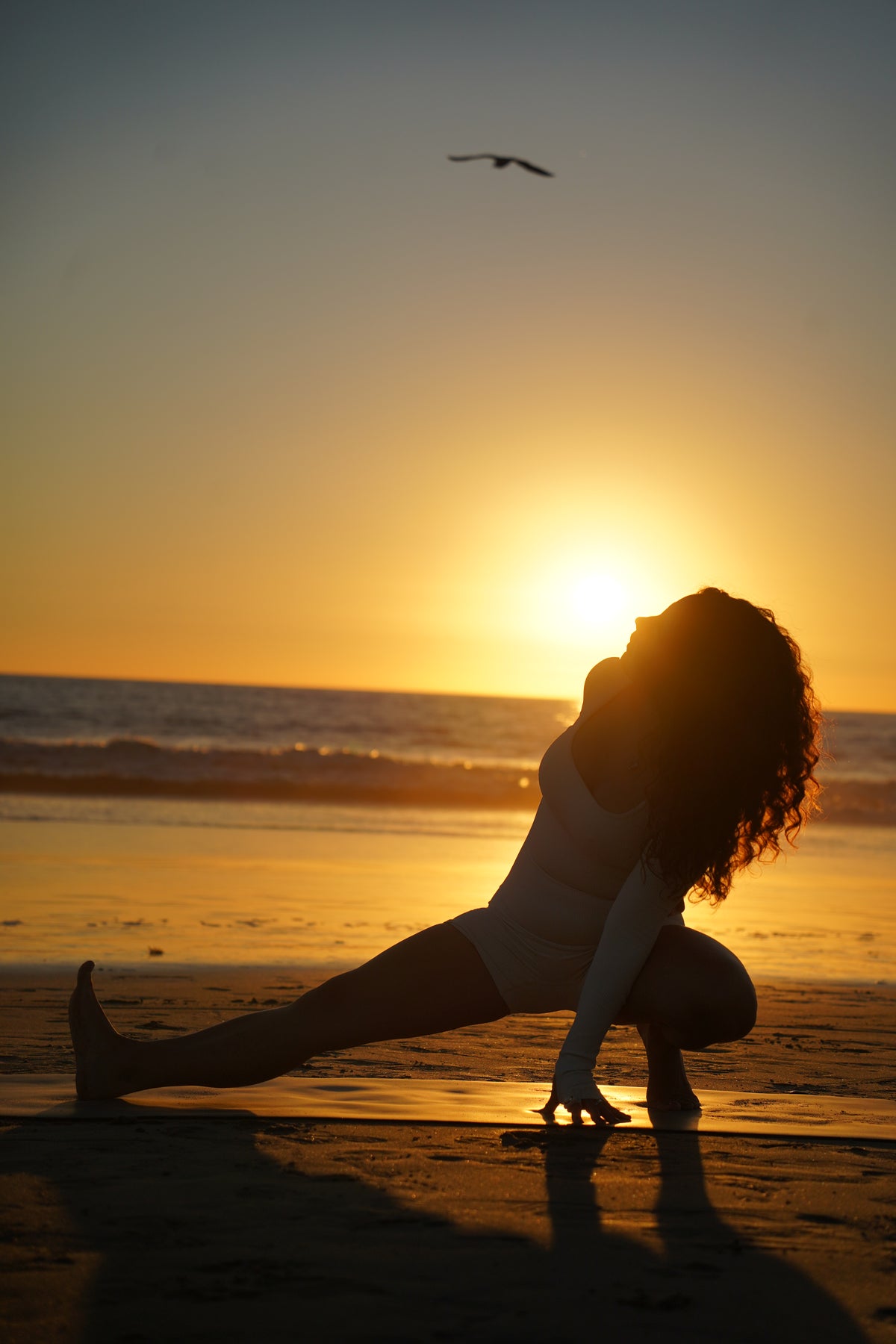 Práctica de yoga en la playa con el sol sobre el horizonte.