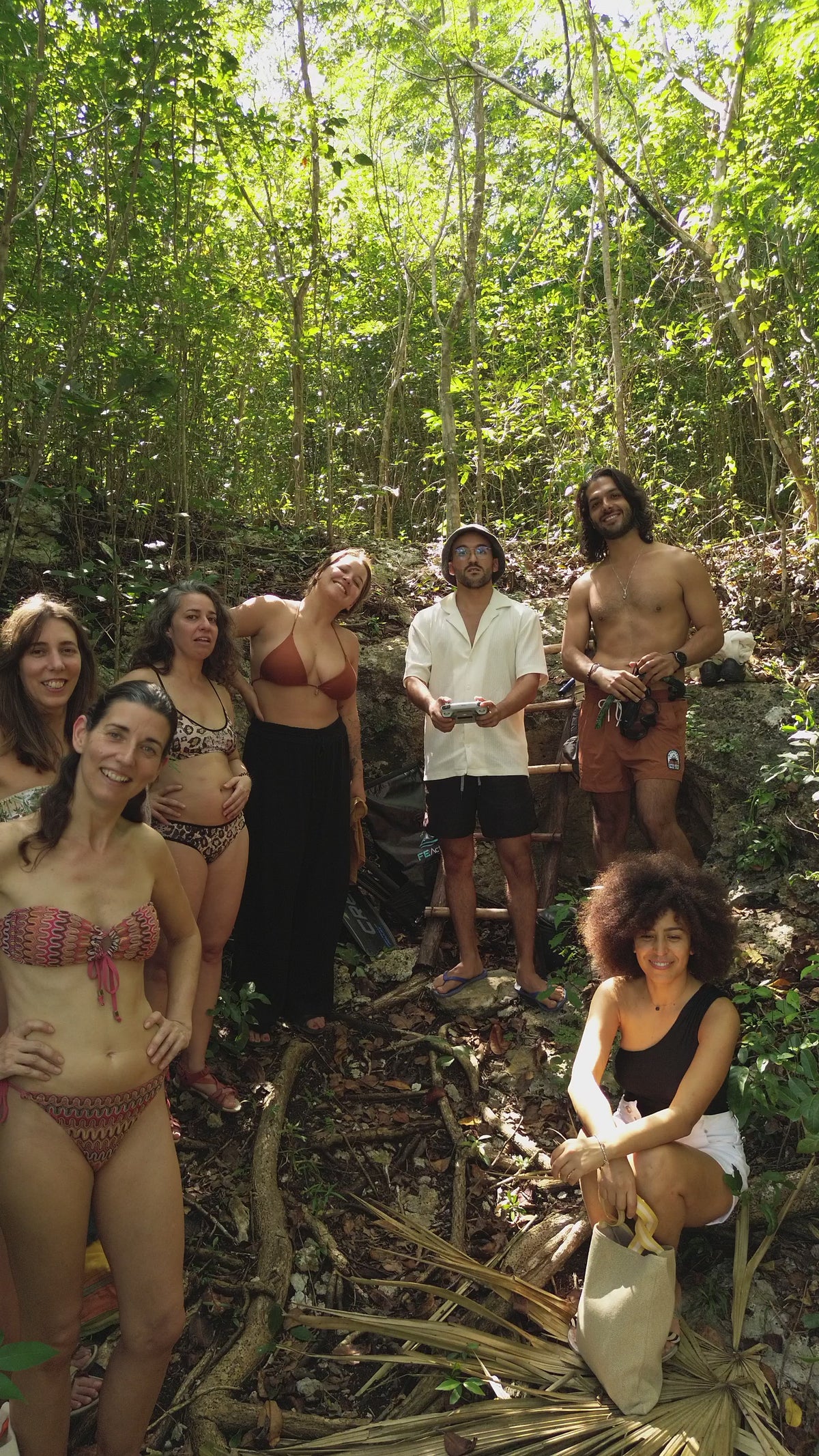 Recorrido de dron que se aleja de un grupo en la selva y revela el cenote.